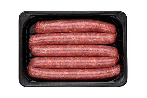 Raw sausages on a white background. Grilled sausages in a plastic container close-up.