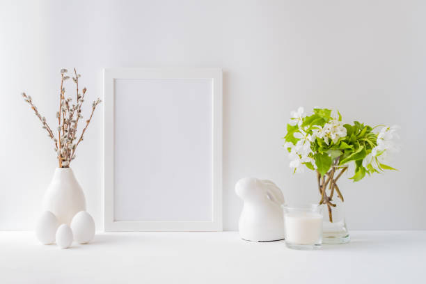 istock Home interior with easter decor. Mockup with a white frame and spring flowers in a vases on a light background 1208633896