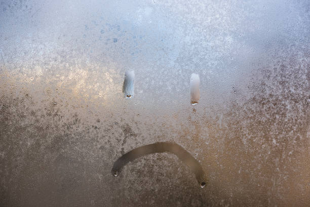 istock sad smiley face on a frozen window covered with frost 1208634509
