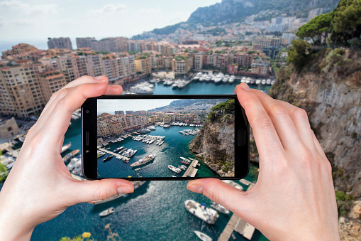The view of luxury yachts and apartments in Monaco. tourist takes a photo.