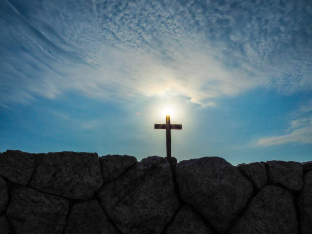 Holy cross with blue sky Silhouette holy cross on stone  against  sunrise  blue sky and white cloud. hope god lighting technique tree stock pictures, royalty-free photos & images