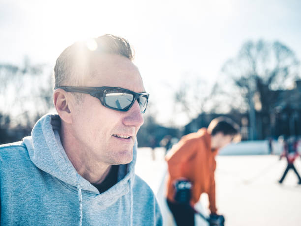 padre e hijo jugando hockey al aire libre - ice skating ice hockey child family fotografías e imágenes de stock