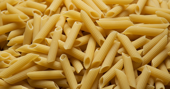 Organic uncooked Italian penne pasta full frame close up from above