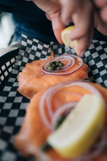 Taken in a restaurant, a person is squeezing lemon on her salmon bagel in Canmore.