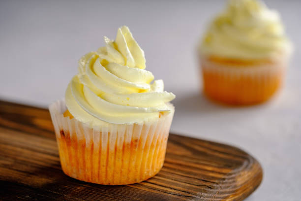 istock Delicate and delicious lemon cupcakes with cream on a wooden board 1208643540