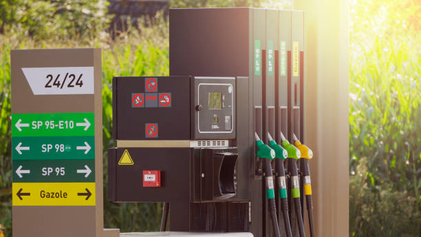 Fuel pumps at a gas station, informations signs. Fuel nozzle in oil dispenser. Petrol gun filling green and golden colors. Gas station open 24/24 in back light with sign of SP 95, SP 98 SP 95 and gazole. benzine stock pictures, royalty-free photos & images