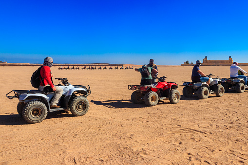 Carefree couples having fun while driving quad bike in the desert. Focus is on couple in the background.