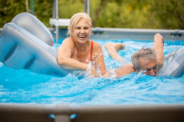 istock Senior couple having fun in pool 1208652826