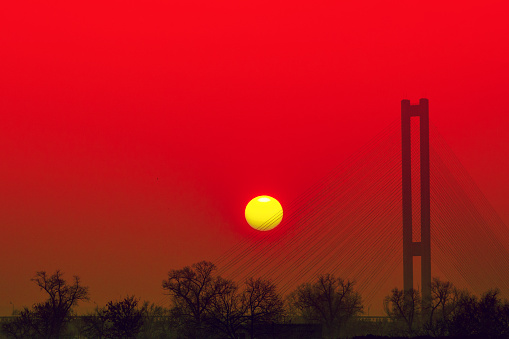 Beautiful evening landscape with the cable-stayed bridge on a background of a dramatic sunset