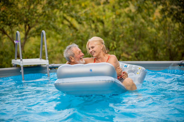istock Senior couple having fun in pool 1208652877