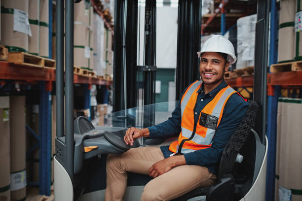 istock Happy young african forklift manager transporting goods from one shelf to another while looking in camera in warehouse 1208654449
