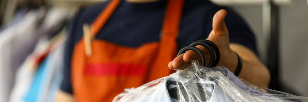 istock Clothes dry cleaning service worker returning shirts to customer 1208659571