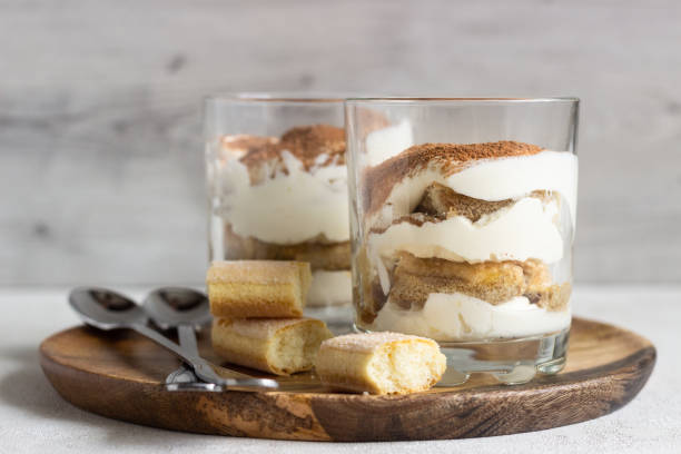 tiramisù da dessert tradizionale italiano in vetro su sfondo grigio chiaro. dolce italiano aromatizzato al caffè a base di ladyfingers e mascarpone. - biscotti italian cuisine italian culture breakfast foto e immagini stock