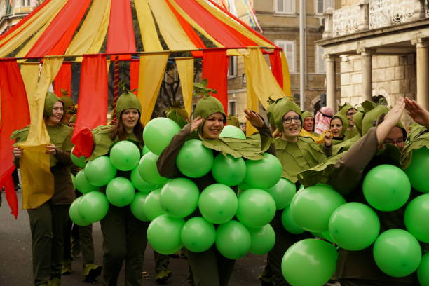 um grupo de jovens mascarados com trajes verdes cercados por balões verdes alegres caminham na procissão do carnaval - laughing street party carnival beauty - fotografias e filmes do acervo