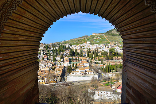 Granada, Spain - February 20, 2020: City of Granada seen through a window of the Tower of the Ladies of the Alhambra in Granada.