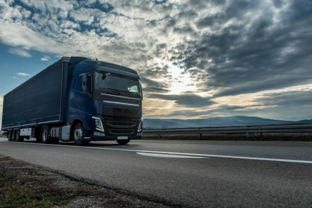 istock Blue semi trailer truck on a highway at sunset 1208666517