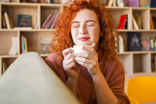 istock Woman sitting on sofa with mug of coffee 1208666572