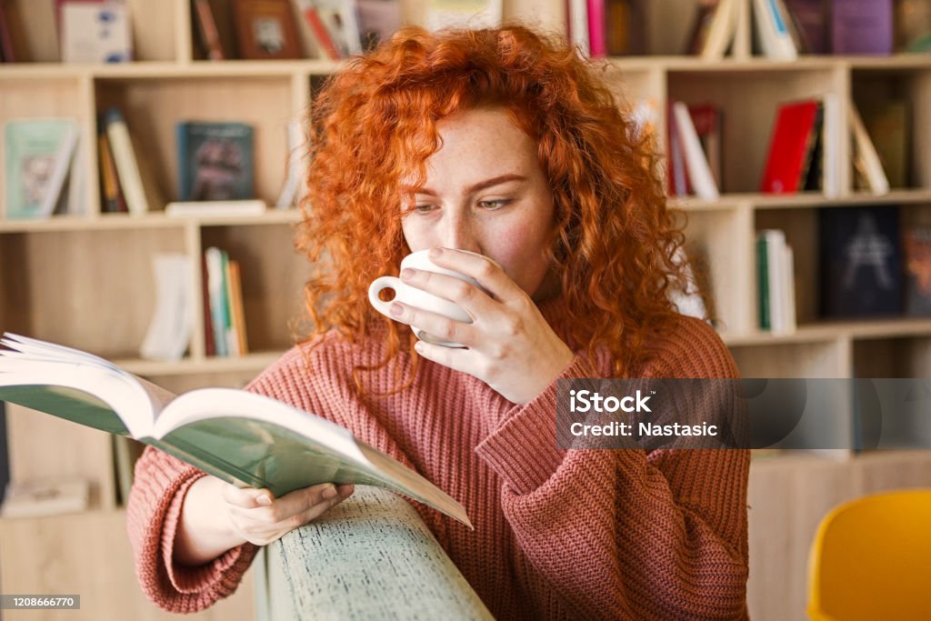 坐在一張咖啡的茶上，在書店看書 - 免版稅讀圖庫照片