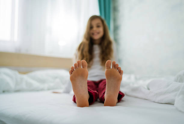 Cute barefoot girl enjoying in bed in morning