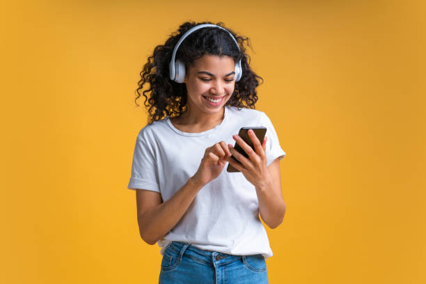 音楽を聴くワイヤレスヘッドフォンを身に着けている魅力的な若いアフリカ系アメリカ人の女の子の肖像画 - skin singer ストックフォトと画像