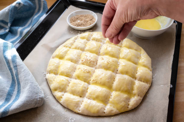 istock Hand is pouring sesame seed on a flat bread dough for baking a Turkish Ramadan Pide 1208675349