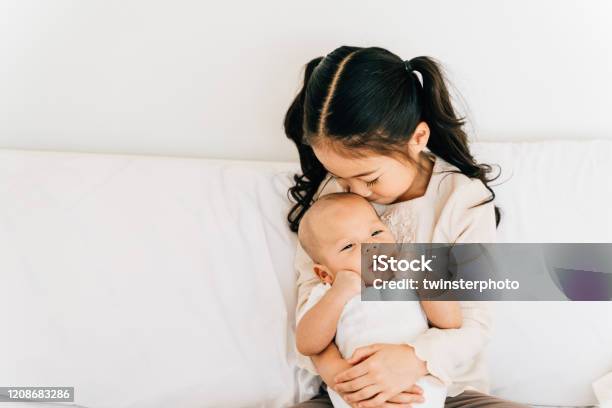 Asian Child Hugging Newborn Baby On Bed Stock Photo - Download Image Now - Sibling, Baby - Human Age, Brother