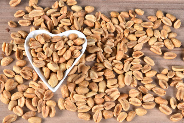 istock delicious and nutritious peanuts, peeled in a heart-shaped bowl with overhead view isolated on wooden table 1208689494