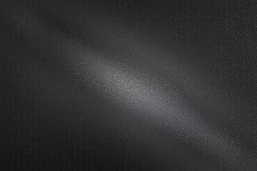 Light shining through on black dirt metal wall in dark room, abstract texture background