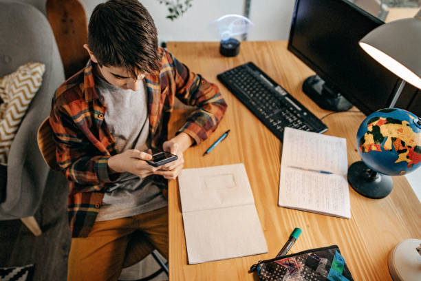 nastoletni chłopiec używający smartfona do wysyłania wiadomości tekstowych - homework teenager mobile phone school zdjęcia i obrazy z banku zdjęć