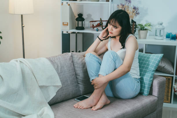 istock Depressed young woman sitting on couch 1208701183
