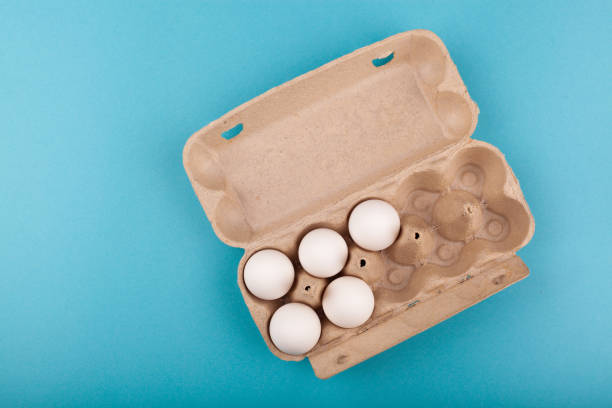 istock Egg Chicken eggs. Top view of an open gray box with white eggs. Isolated on a blue background. The concept of a healthy lifestyle, getting pure protein. Proper Breakfast. Five eggs 1208702295