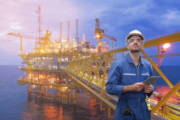istock Caucasian man engineer staff worker with tablet in hand and offshore rig background concept. 1208704315