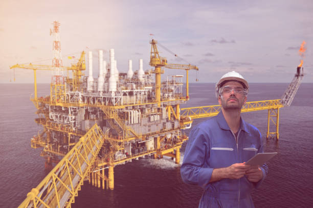 istock Caucasian man engineer staff worker with tablet in hand and offshore rig background concept. 1208704316
