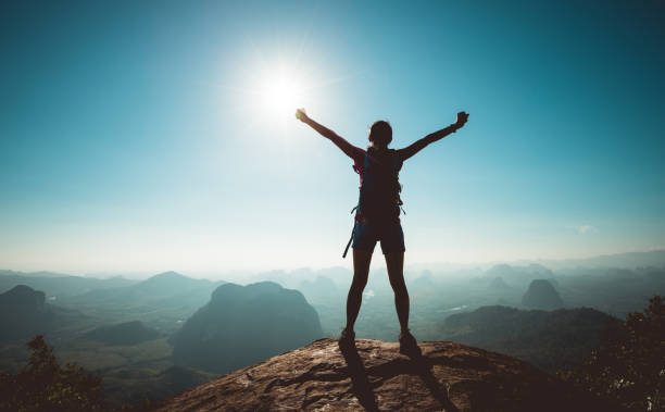 istock Cheering woman backpacker enjoy the view on sunrise mountain top cliff edge 1208704349