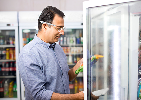 Man with shopping list checking product information in supermarket