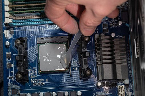 Applying thermal paste with spatula in CPU on motherboard. Close up