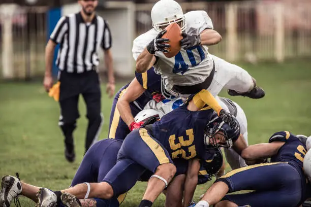 Large group of tough American football players in action during the game on playing field.