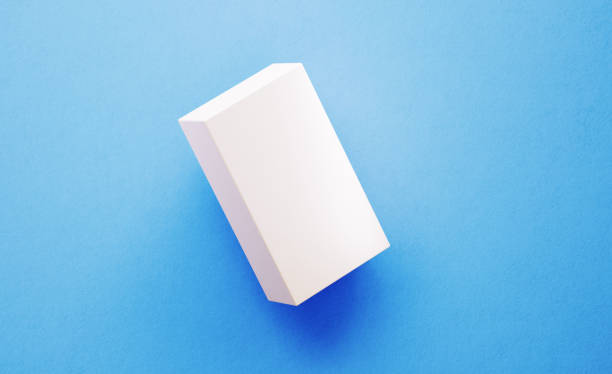 White tea and coffee paper package sitting on blue background. Coffee package is lit by the upper left corner of the composition and casting shadows on the ground. Great use for logo and product placement.