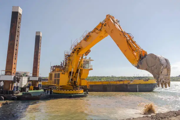 Dredging. A floating excavator drips soil from the seabed with a huge bucket
