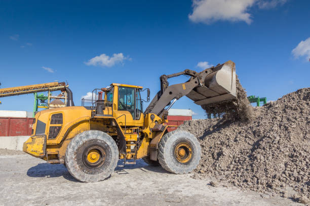 istock Frontal bucket loader loads clay into a stack in an open warehouse. The load is pouring from the bucket 1208746388
