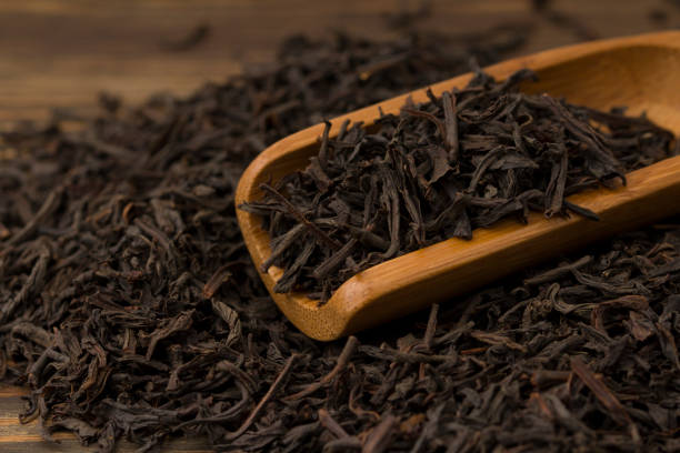 istock Scattered leaves of black tea on a wooden table. 1208746463