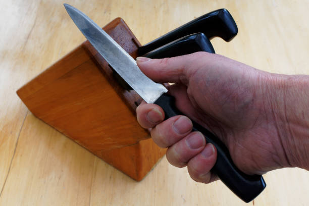 Woman is sharpening a kitchen knife using knife sharpener in domestic kitchen