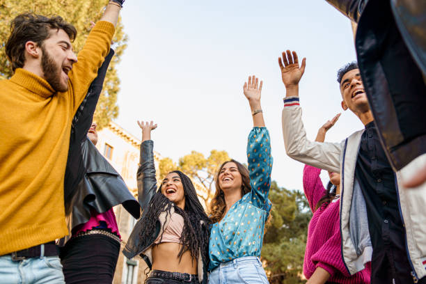 istock Joyful young people hands raised up. Group of multiracial people having fun together. Unity, togetherness and friendship lifestyle concept. 1208752763