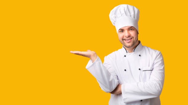 istock Chef Man Holding Invisible Object On Open Palm, Yellow Background 1208753988