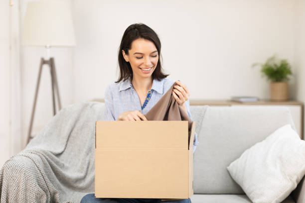 istock Smiling girl putting clothes in cardboard box 1208755073