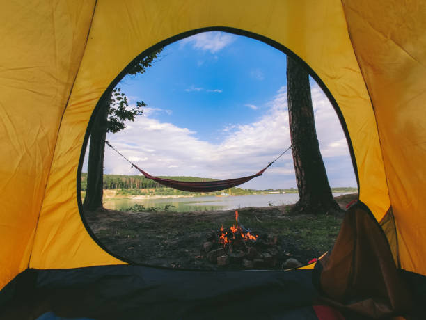 vue forme tente de camping sur le feu de camp avec hamac près du lac - beach on child the photos et images de collection