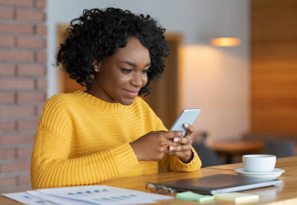 istock Busy cheerful black girl chatting at cafe, using smartphone 1208757449