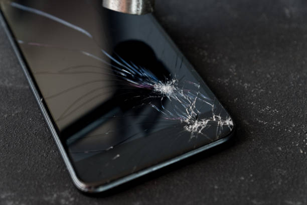 istock Smartphone with broken glass screen and hammer on dark background. 1208757501