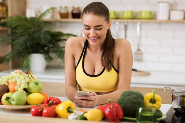 istock Healthy lifestyle. Woman texting on phone in kitchen 1208757532