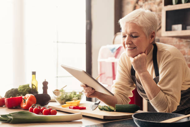 istock Elderly woman using digital tablet in kitchen, checking cooking recipes 1208757593